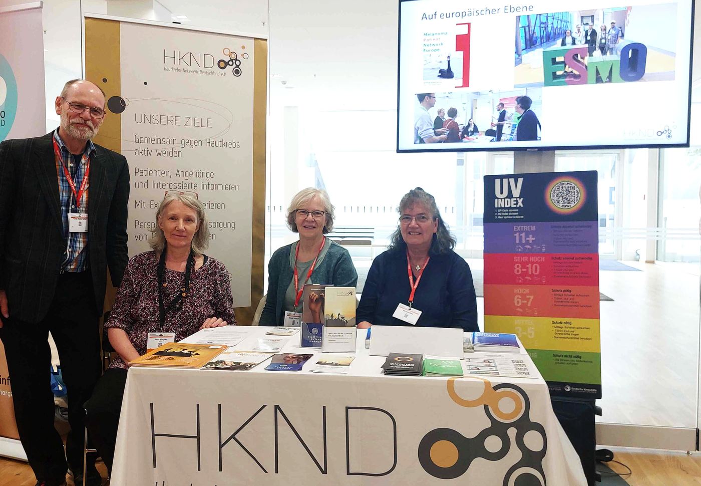 Vier Personen stehen und sitzen am Infostand des Hautkrebs-Netzwerks Deutschland e.V.